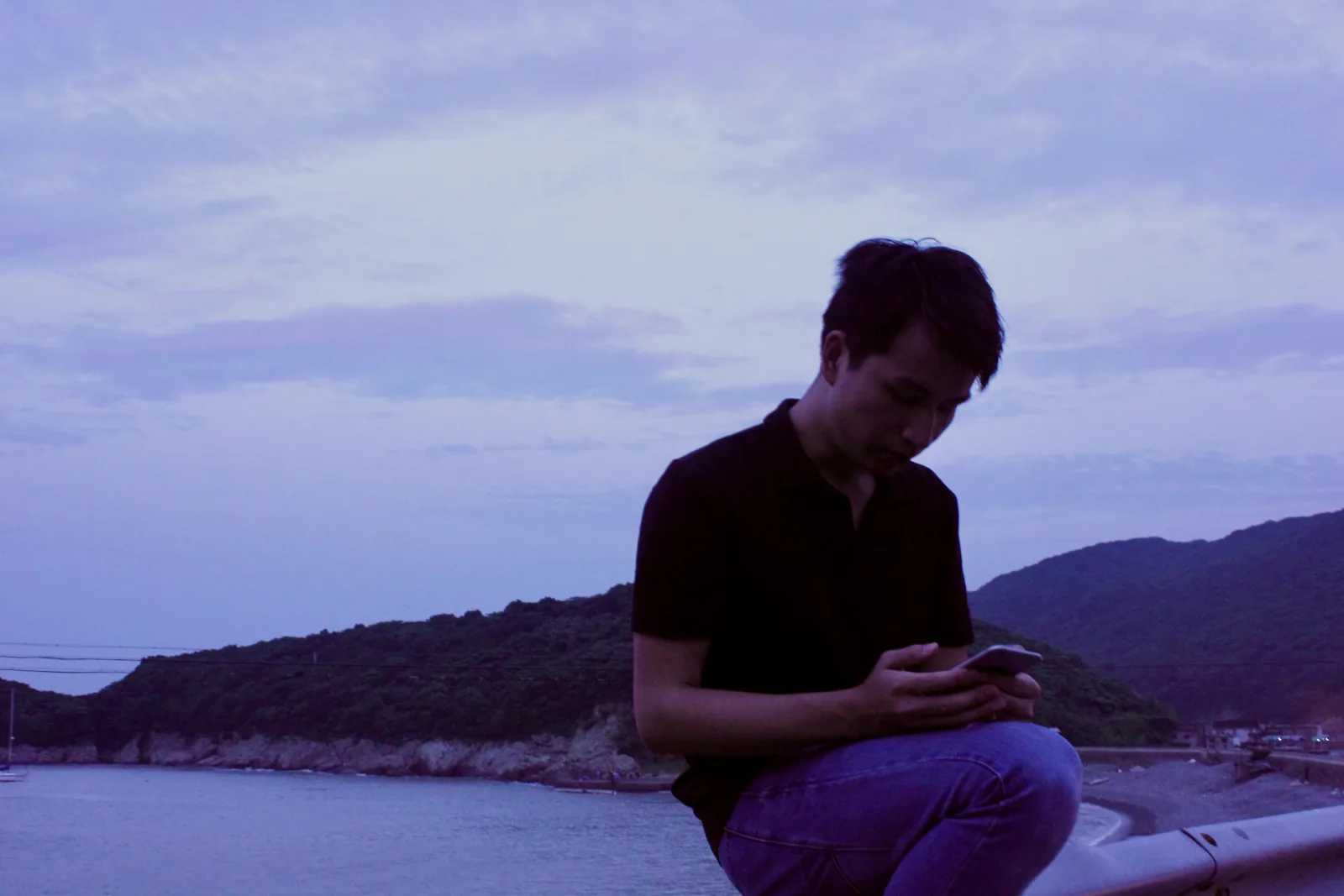 暮色中坐在东极岛海边看手机的人
