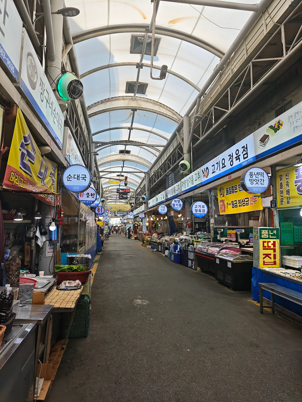 广藏市场内景：顶棚下两侧食肆密密麻麻，人贴人往前走