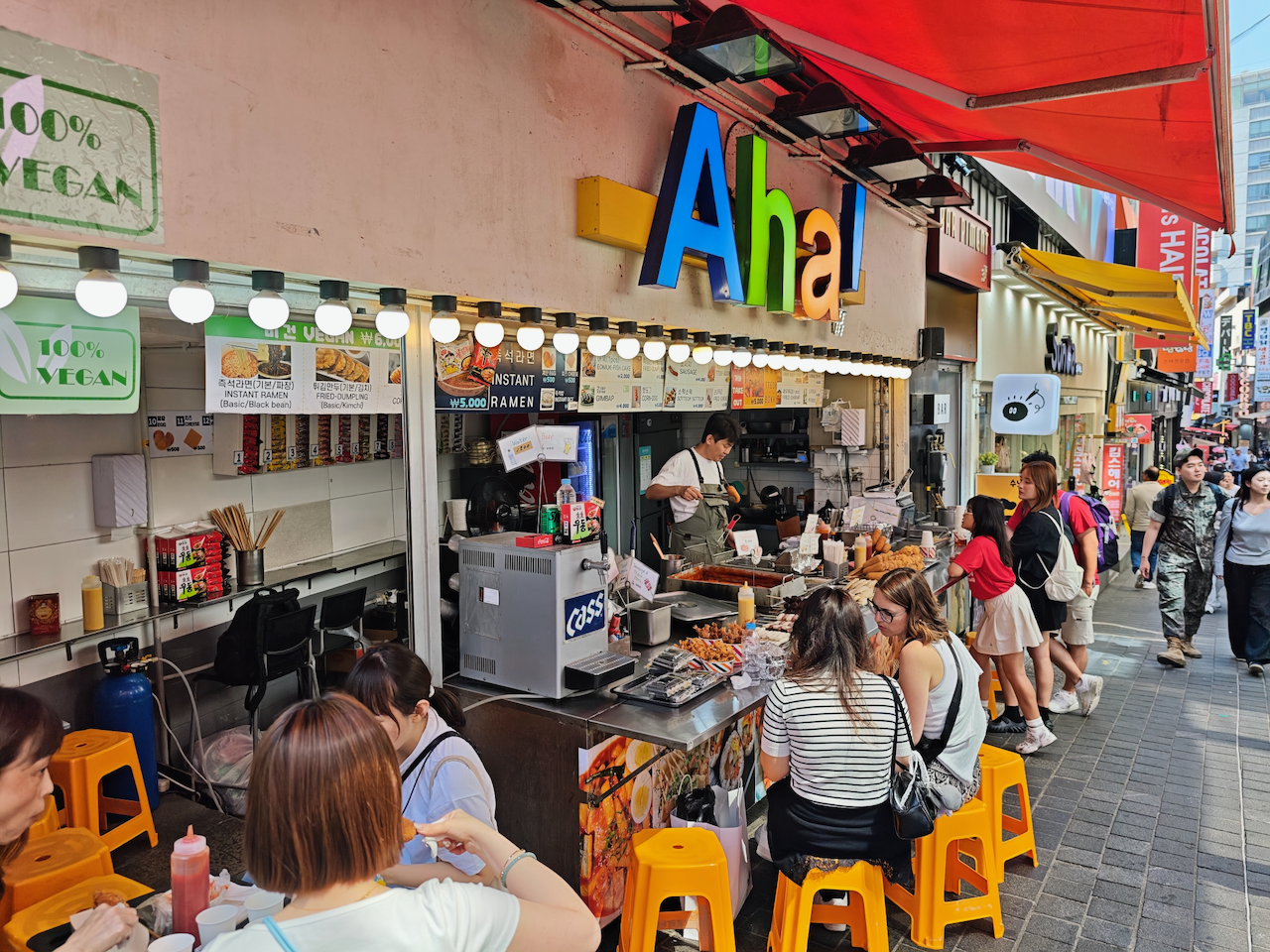 明洞街边小吃店"Aha!"，塑料凳上坐满了人