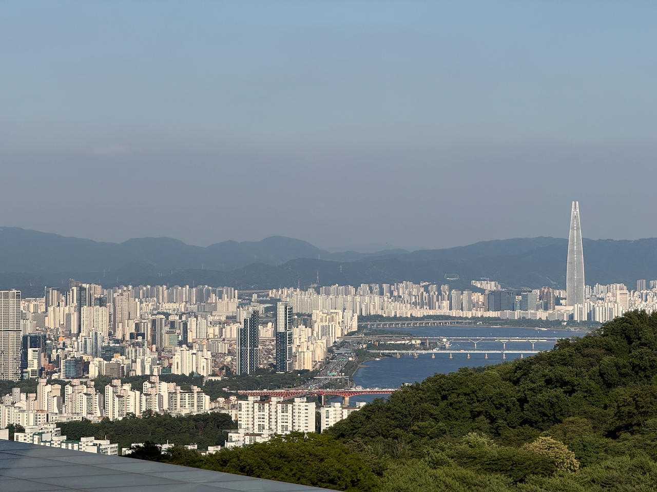 从塔上俯瞰，乐天塔在城市中央，远处是山