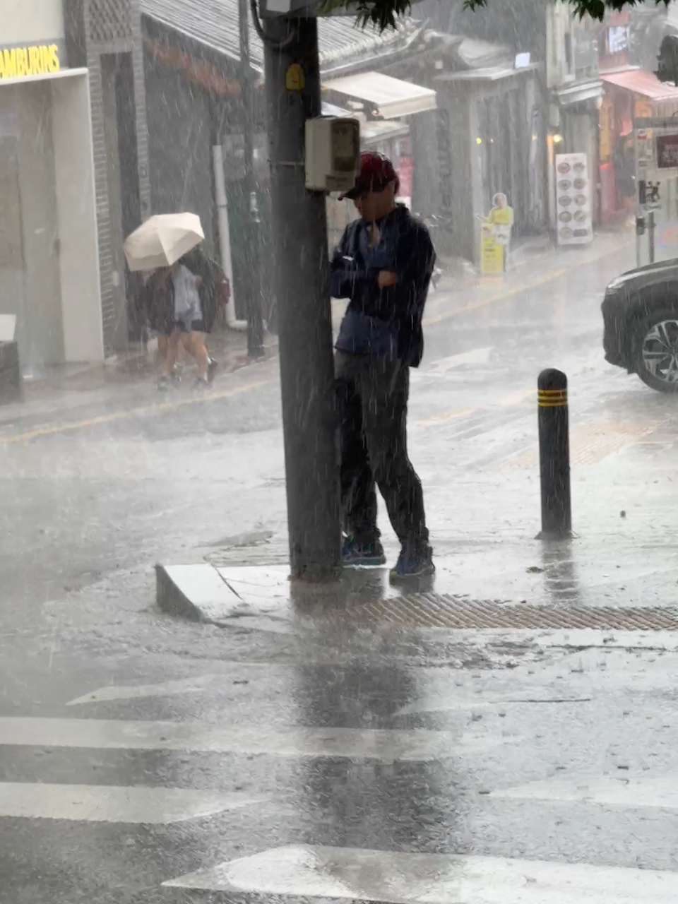 暴雨里一个撑伞的行人，旁边是停在路边的黑色现代车 14:39:43